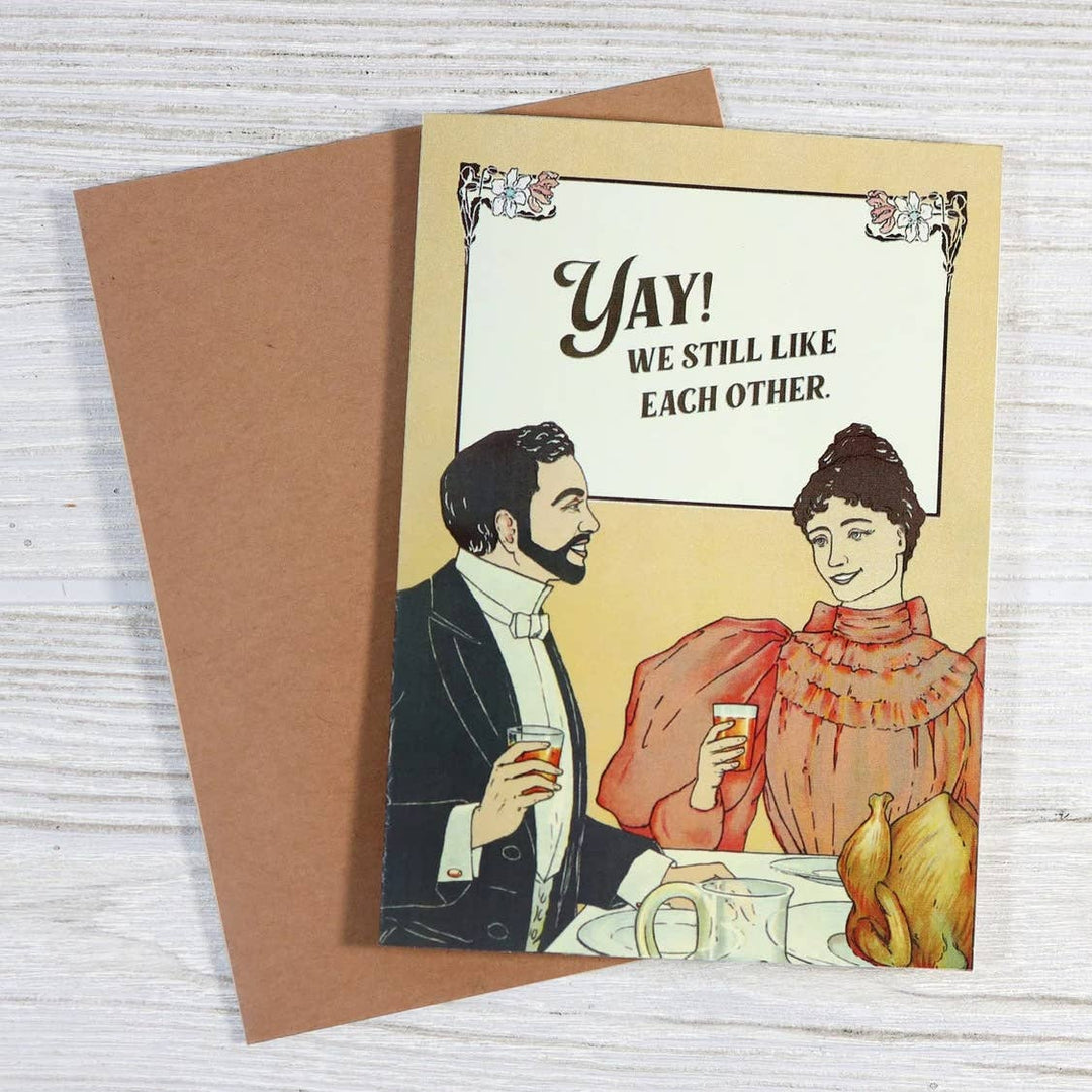 Vintage-style greeting card with illustration of a couple and text 'YAY! WE STILL LIKE EACH OTHER.' 