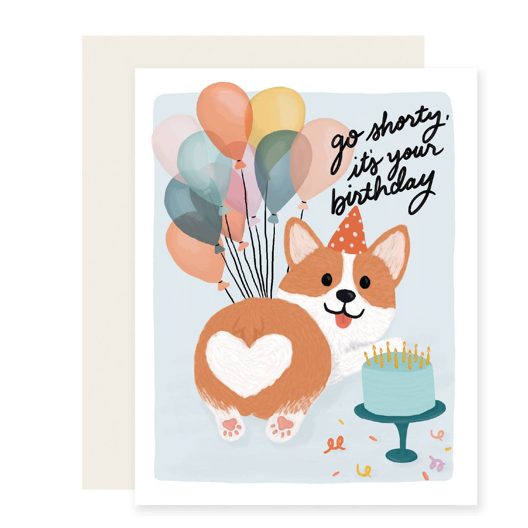 Smiling corgi holding a bouquet of balloons next to a cake. Black script letters say "go shorty. it's your birthday."