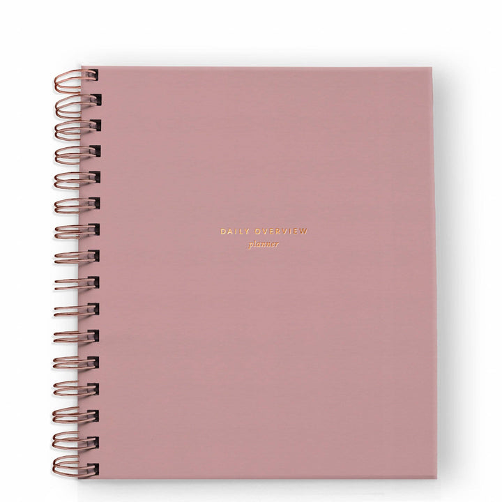 Cover of daily planner in dusty rose with gold spiral binding on the left side.