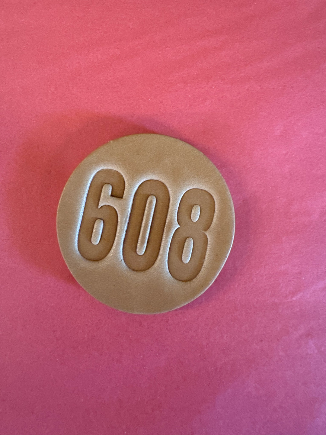 Round leather magnet with "608" stamped in large letters.