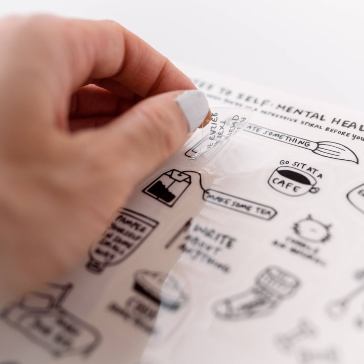 Hand lifting a sticker off a page.