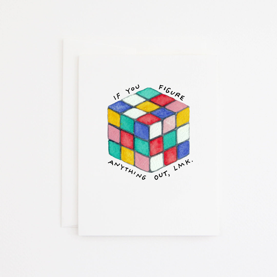 A white greeting card with a hand-drawn multicolor Rubik's cube in the center and the text 'IF YOU FIGURE ANYTHING OUT, LMK.' around it.