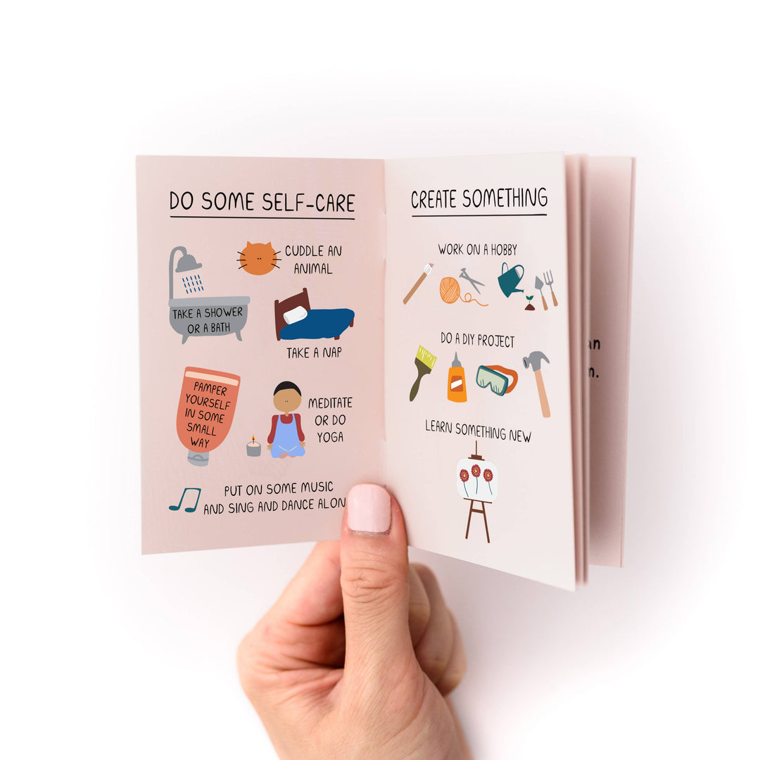 Hand holding a small book with with titles "Do Some Self-Care" and "Create Somethingl" with several examples of each.