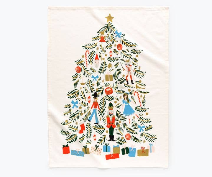 Open tea towel with Nutcracker characters, green branches forming a Christmas tree, with presents underneath, on an off-white background.