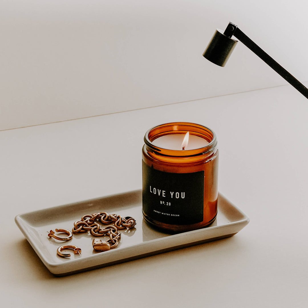 White matte tray holding candle and jewelry.