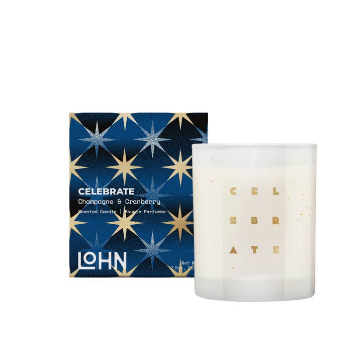 Scented coconut and soy wax candle in a decorative white matte glass container next to its decorated blue gift box. The word celebrate is stamped on the glass in gold.