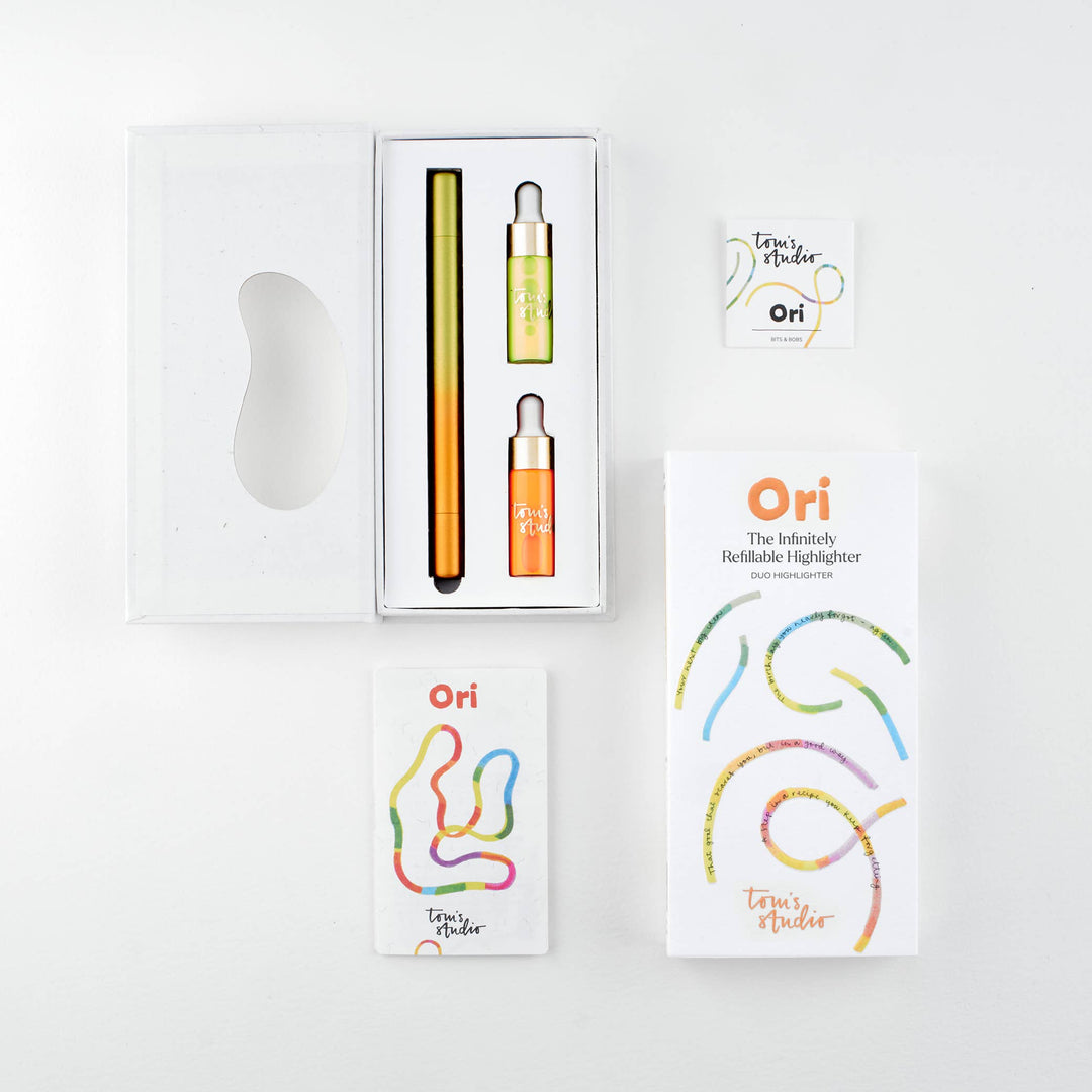 Opened package of the yellow-orange pen with the pen and two containers of ink next to its cover and a booklet.