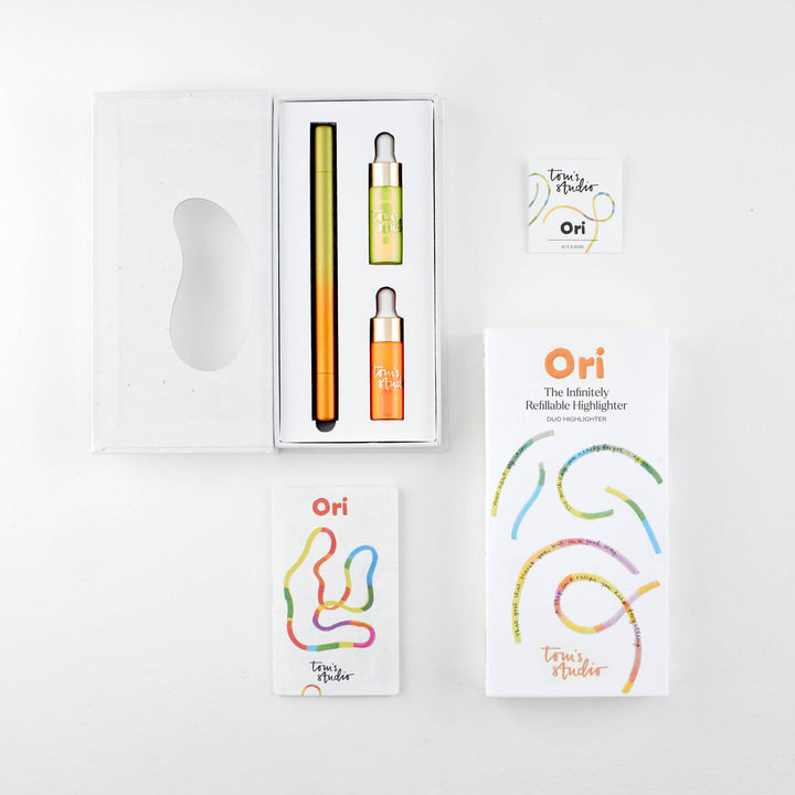 Opened package of the yellow-orange pen with the pen and two containers of ink next to its cover and a booklet.
