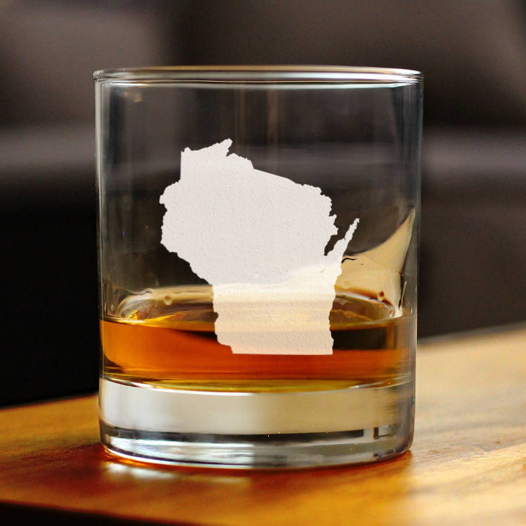 Rocks glass with a map of Wisconsin etched on it, with a thumb's worth of amber liquid.