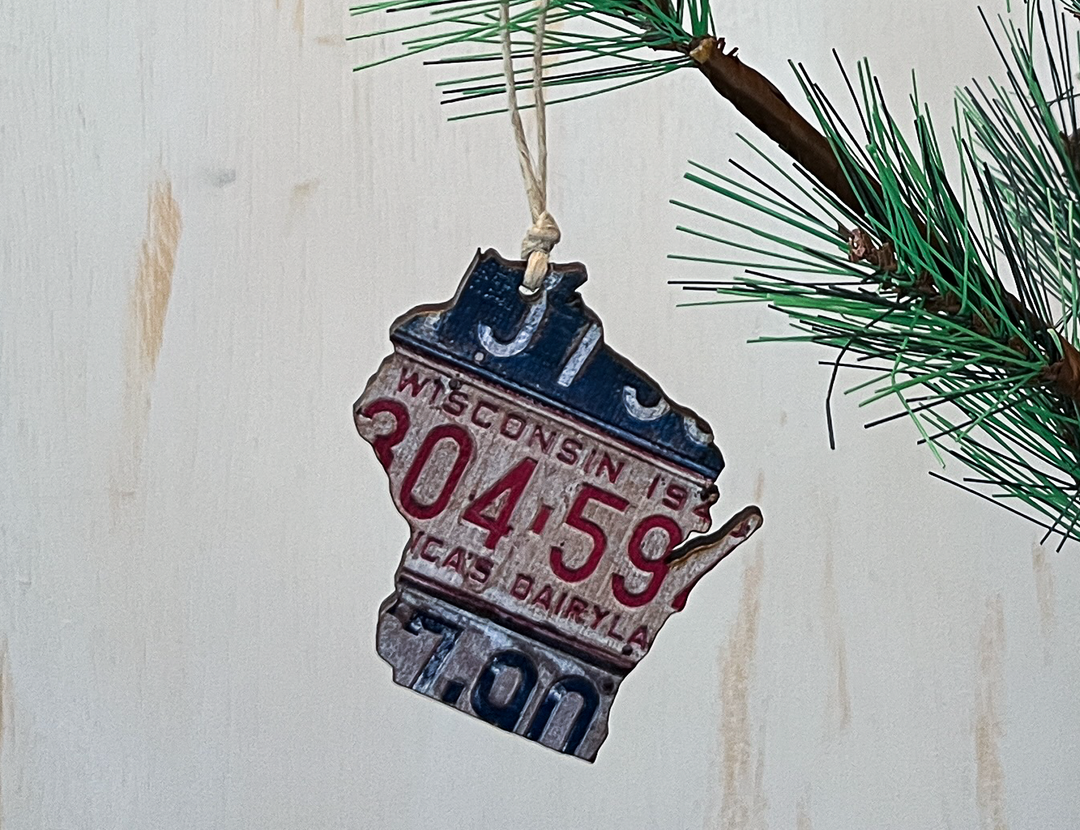 The shape of the state of Wisconsin cut from a vintage license plate with hanging string.