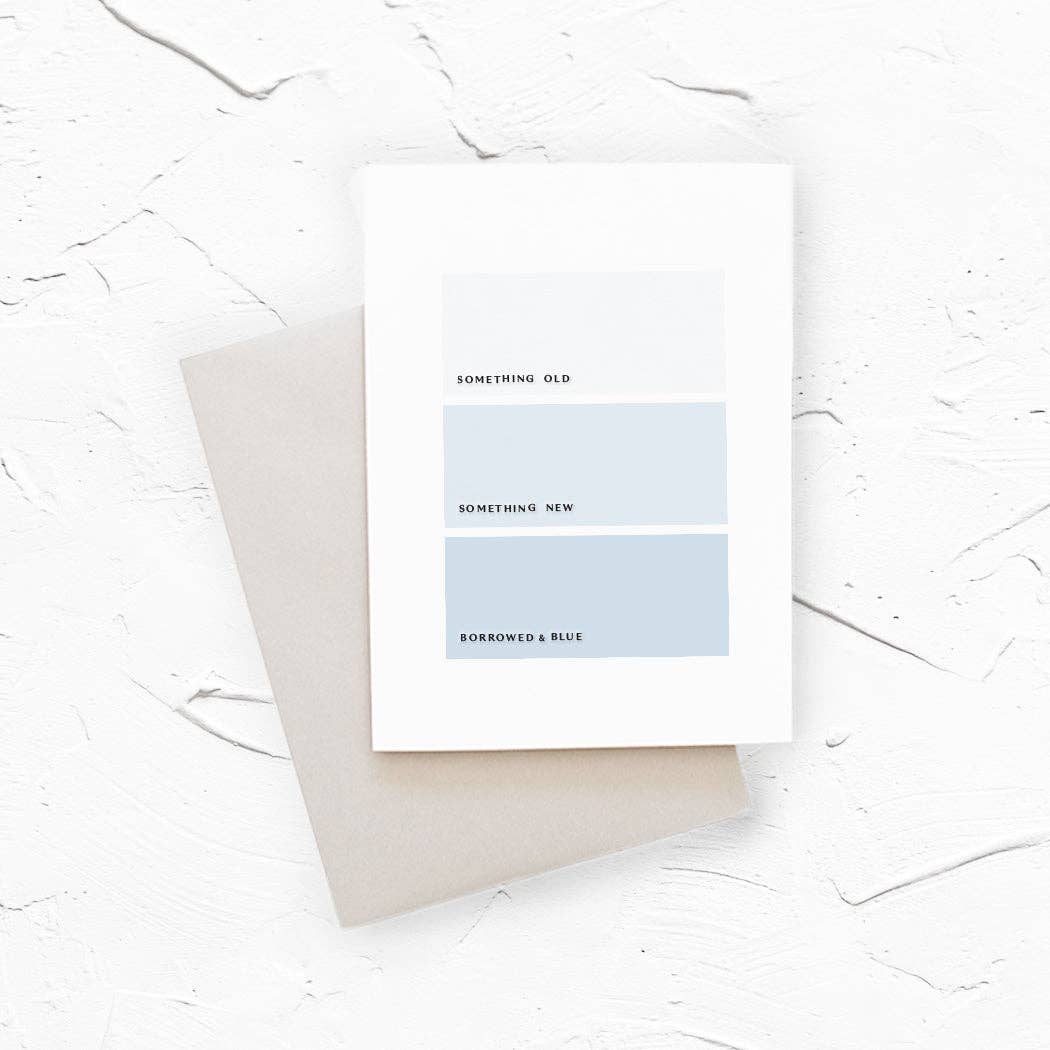 A minimalist art print card with three horizontal color blocks in shades of blue and gray, labeled 'SOMETHING OLD', 'SOMETHING NEW', and 'BORROWED & BLUE', resting on a neutral beige envelope.