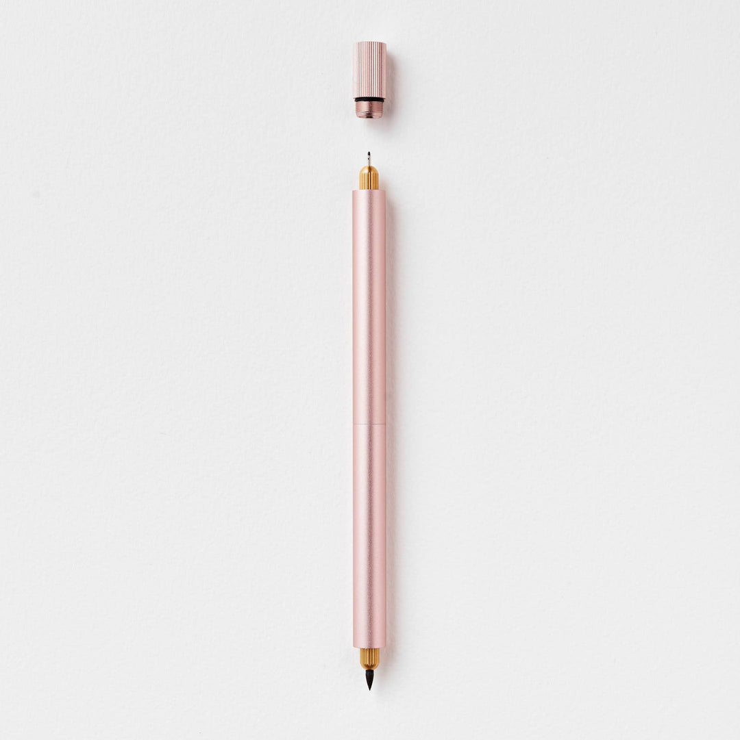 Duo pen in blush with cap suspended above the fineline end.