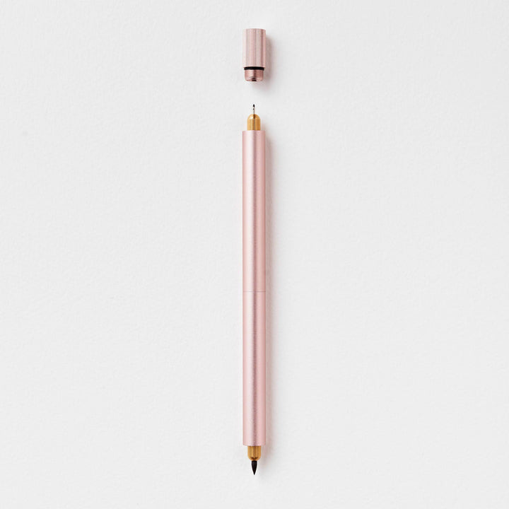 Duo pen in blush with cap suspended above the fineline end.
