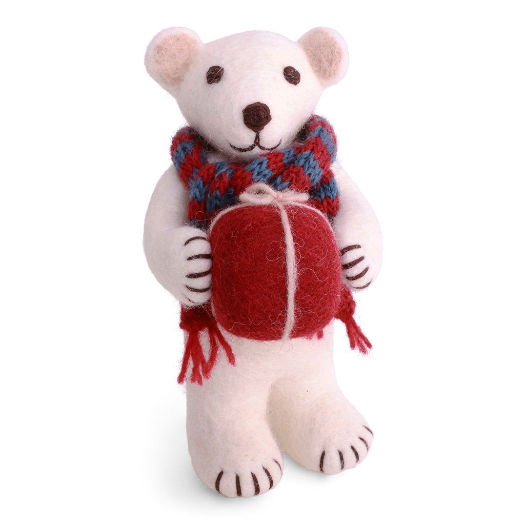A white felt polar bear wearing a red and blue knit scarf and holding red gift with a white bow.