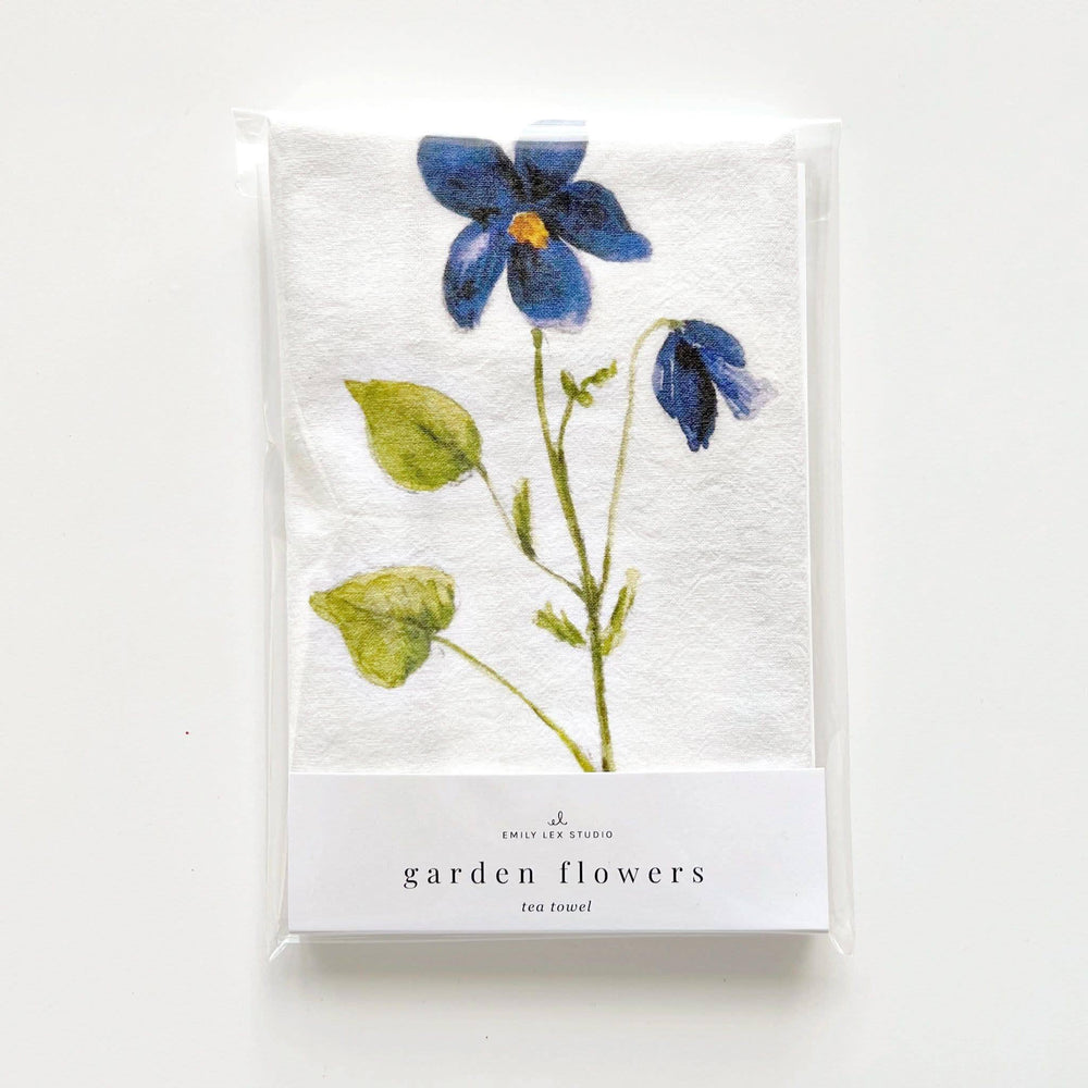 Kitchen towel folded in its package with a stem of a blue flower showing.