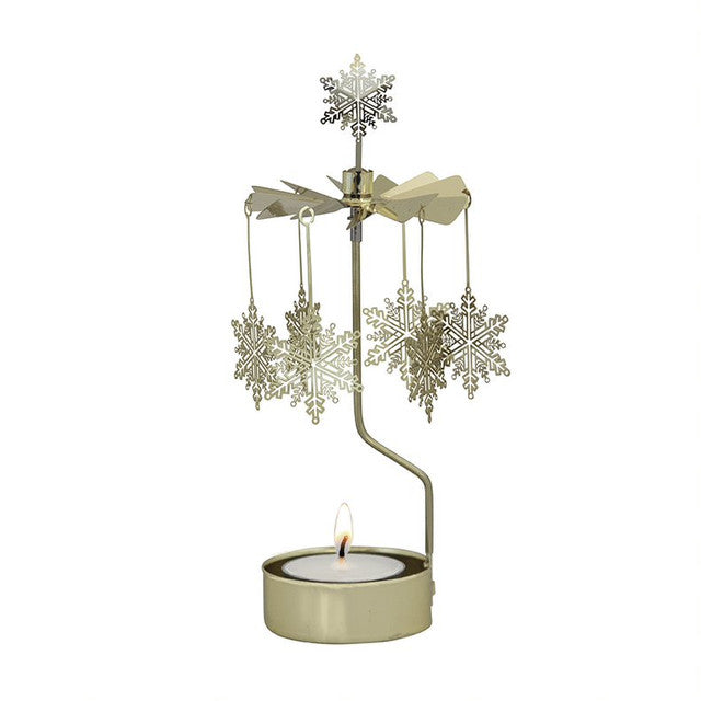 Tea light in a gold holder with vertical arm supporting a carousel of six snowflakes.