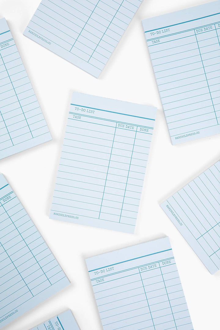 Multiple blue lined notepads, each with dark blue lines on a light blue background to resemble a library due date card.