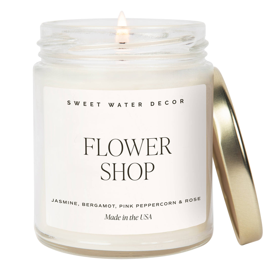 Scented soy candle in a clear glass container with metal lid. Label is Flower Shop Jasmine / Bergamot / Pink Peppercorn / Rose