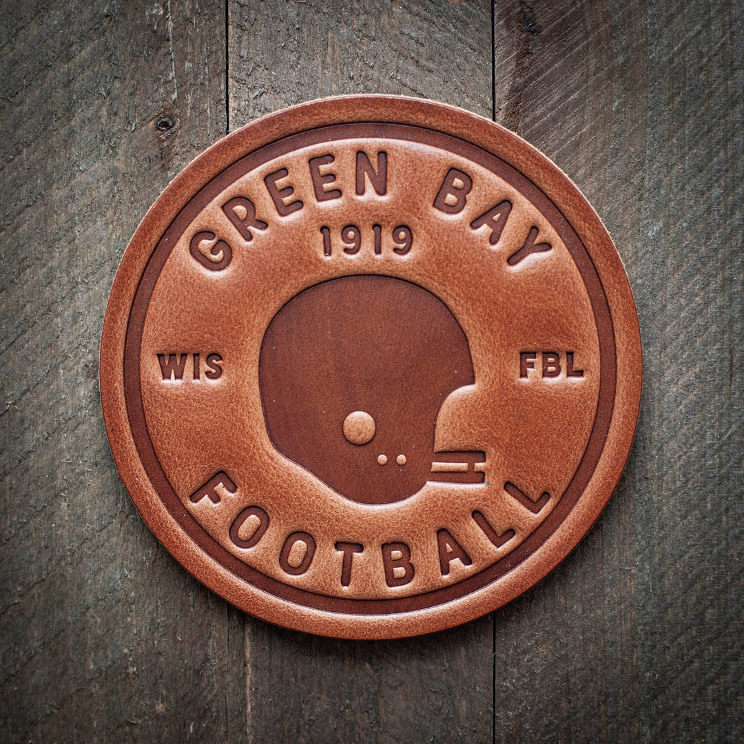 Circular brown leather coaster  with 'Green Bay 1919 WIS FBL' text 