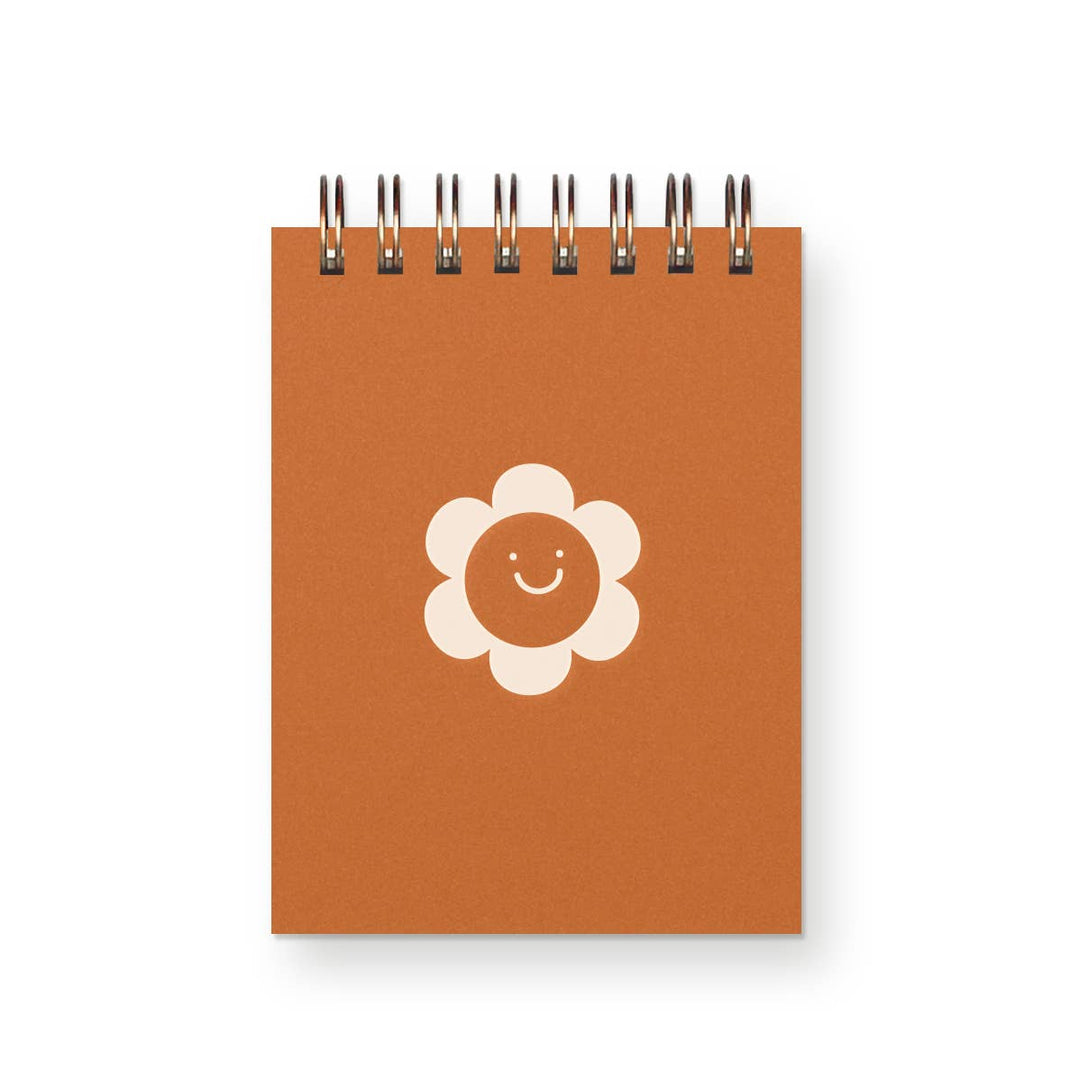 Small spiral-bound notebook with smiling flower on cover