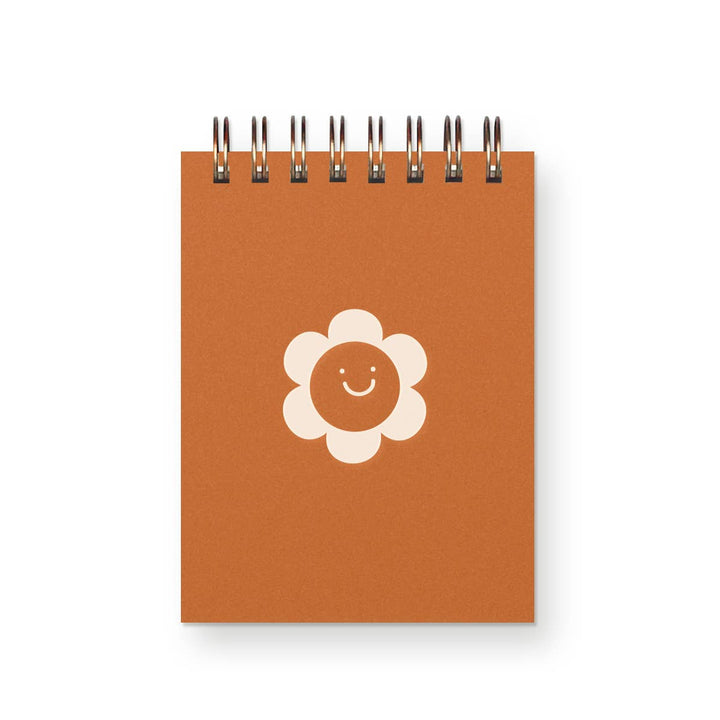 Small spiral-bound notebook with smiling flower on cover