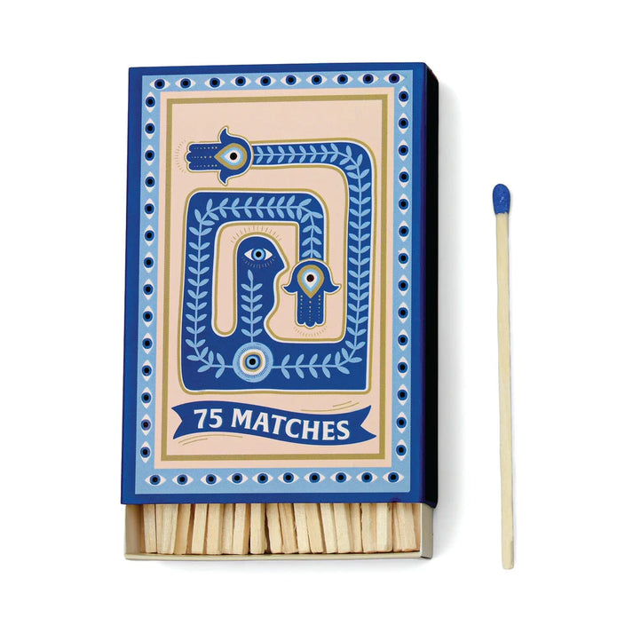 Partially opened matchbox next to a blue-tipped match. "Evil eyes" form a border around the box perimeter. The center includes an abstract drawing in light and dark blue and gold.