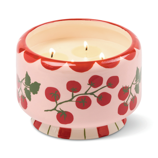 Four lit wicks in a ceramic candle holder with cherry tomato design.