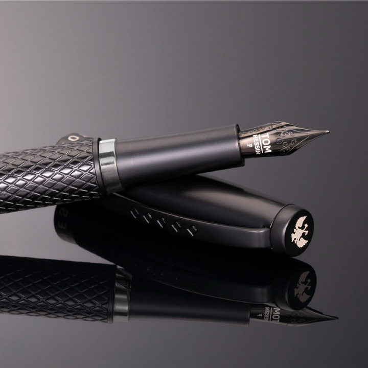 Artful display of the black fountain pen. The pen is resting at an angle on the cap and the image is reflected.