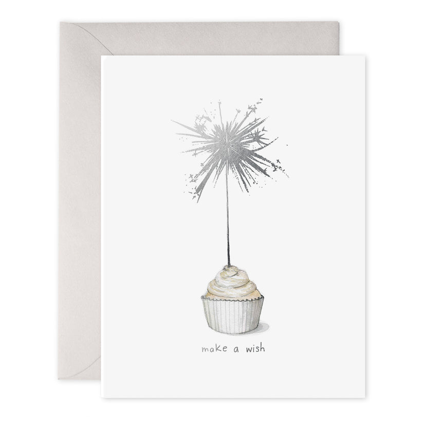 Cupcake with tall sparkler that's lit above text.