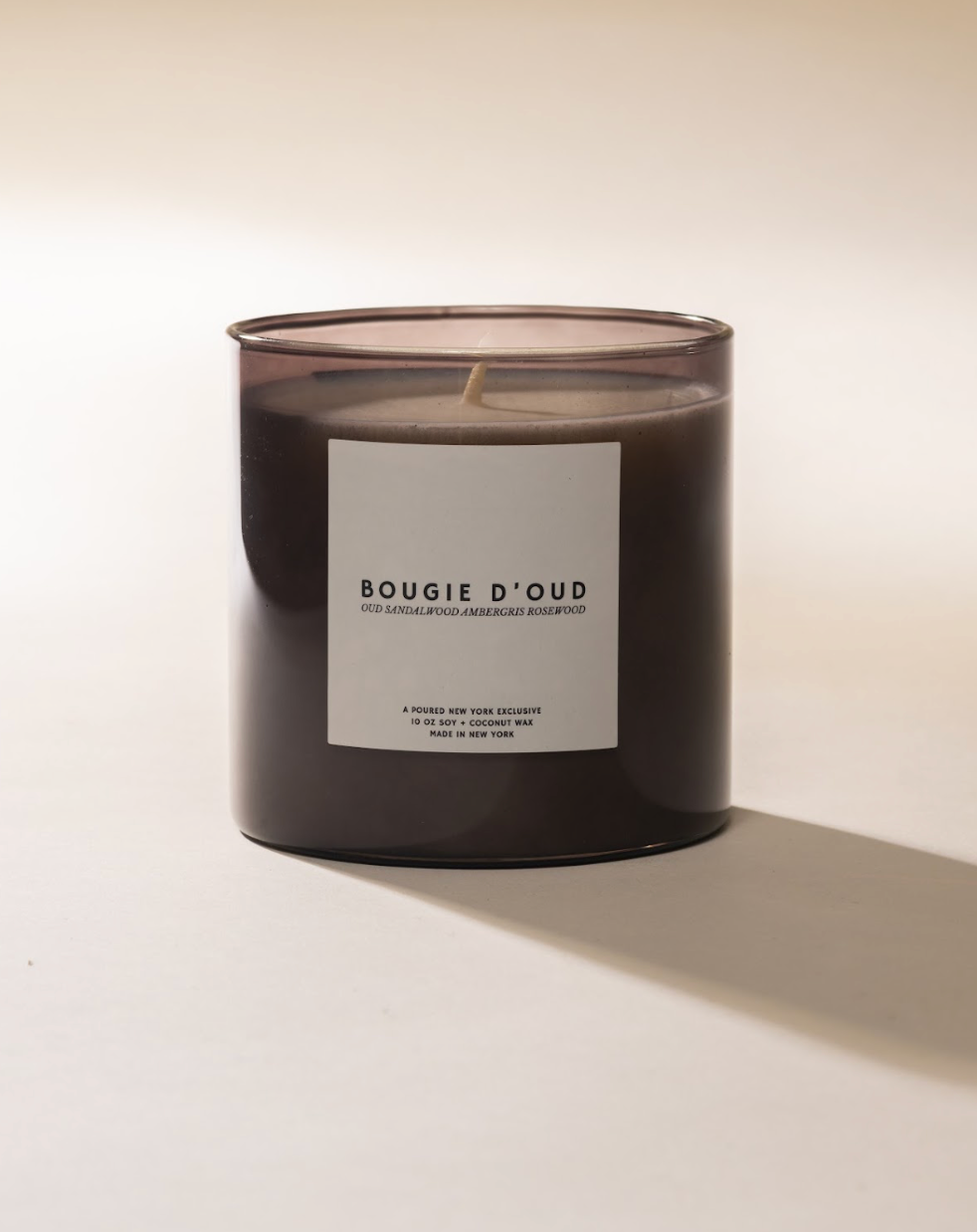 Candle in a clear glass jar with a white label reading 'BOUGIE D'OUD'.