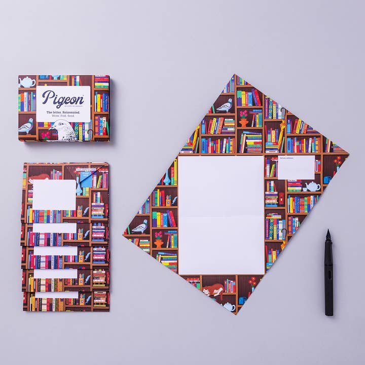 Writing set opened to show five envelopes, each with a different design, and the sixth unfolded to show the writing area, all decorated with books on shelves around white spaces for writing.