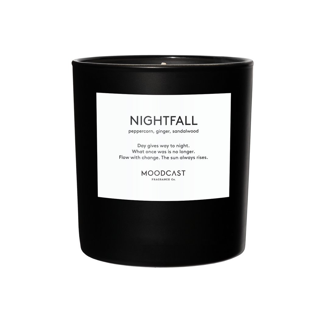 A black glass candle jar with a white rectangular label reading 'NIGHTFALL' and 'MOODCAST Fragrance Co.'.