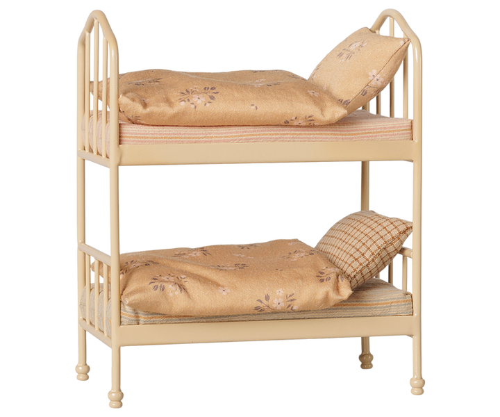 Bunk bed with a cream-colored metal frame, styled with beige floral bedding and pillows.