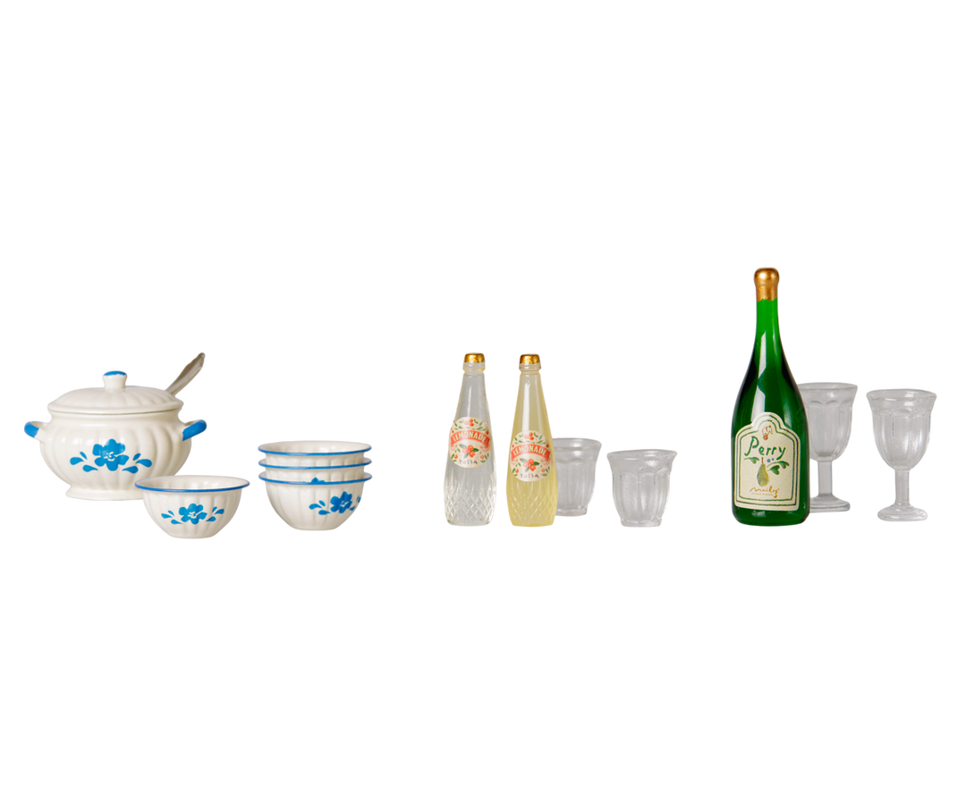 A miniature cooking set featuring a white ceramic soup pot and four bowls in a blue floral patterns, two clear bottles and glasses for the children mice beverage and  a wine bottle and clear glasses for adult mice.