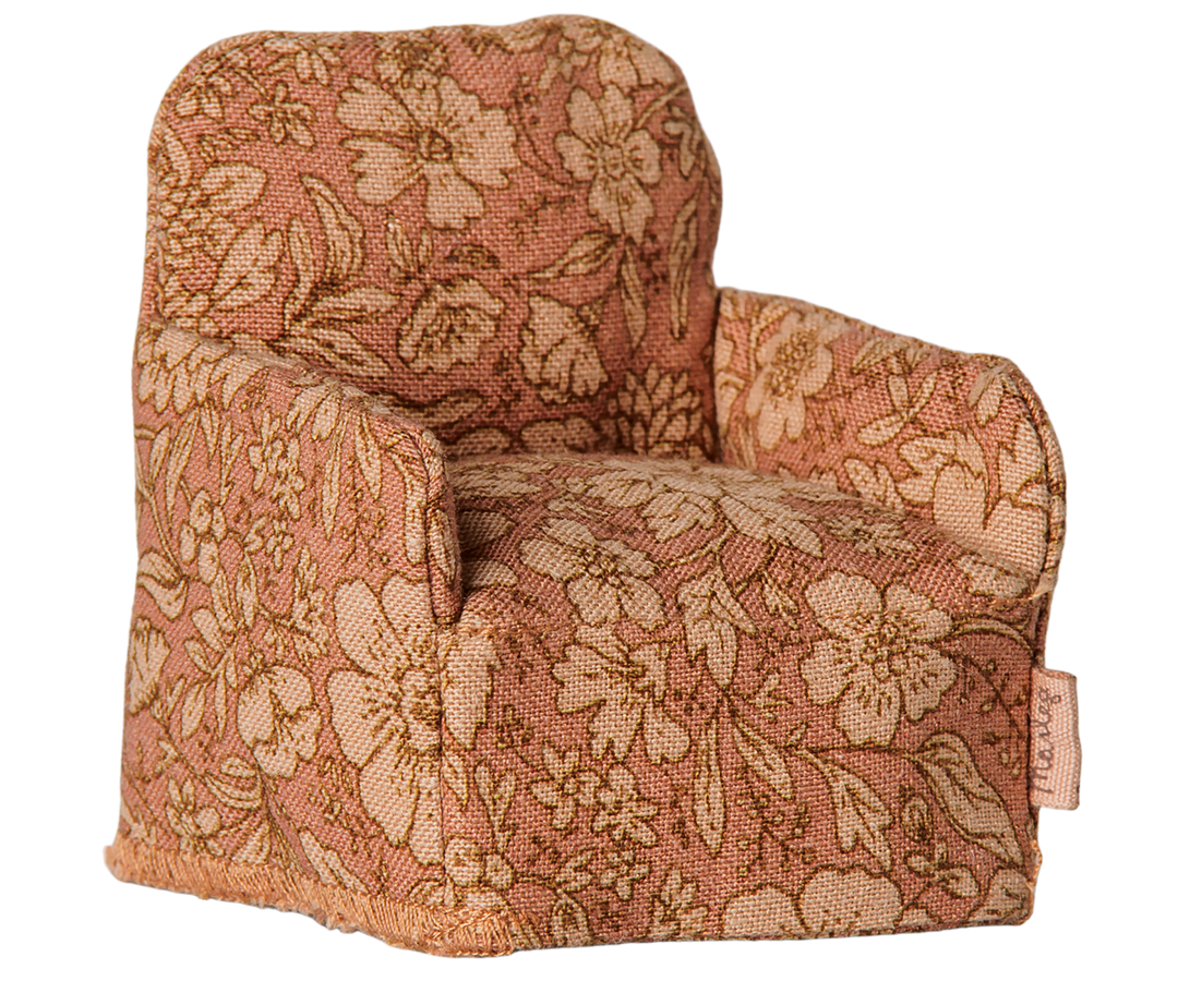 Upholstered armchair with a dusty rose and beige floral pattern.