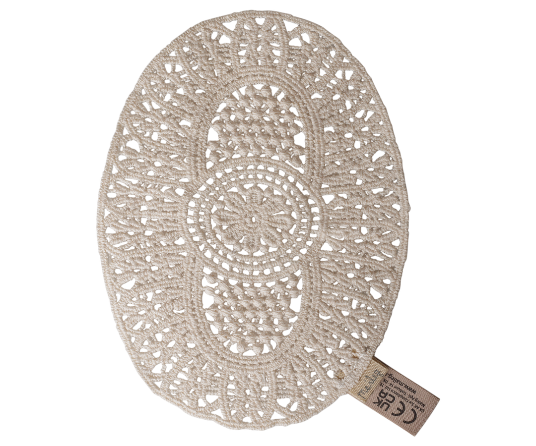 An oval off-white crocheted rug with an intricate openwork lace pattern.