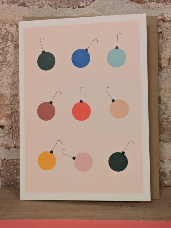 Nine ball ornaments, with hooks each in a different color, placed in a grid, but each leaning in a slightly different direction.