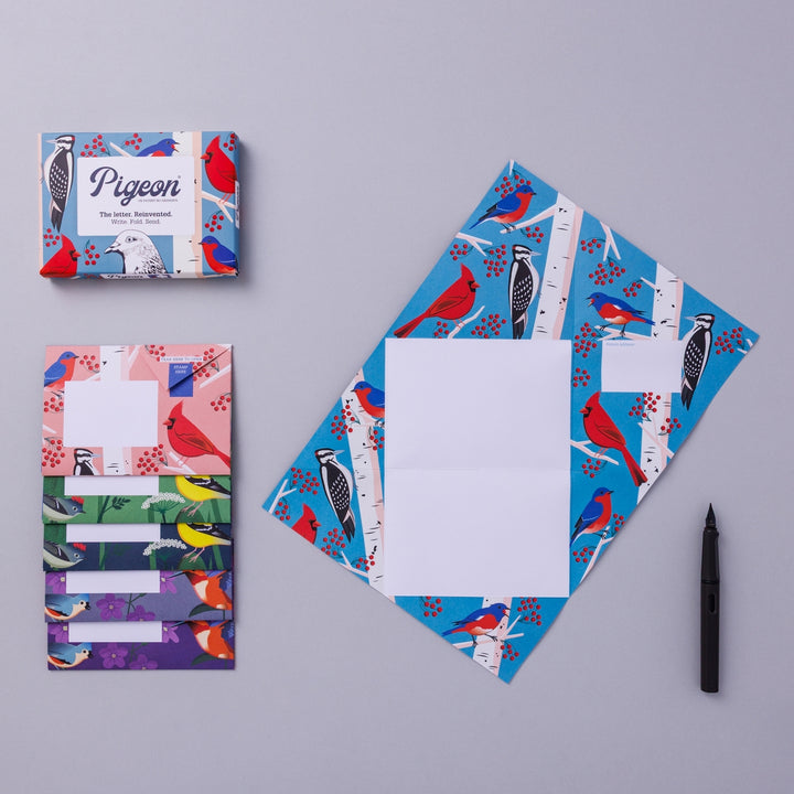 Writing set opened to show five envelopes, each with a different design, and the sixth unfolded to show the writing area, all decorated with bright birds on branches.