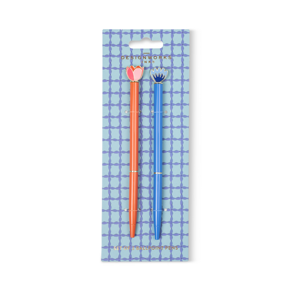Two pens, one orange and one blue, each with a flower at the top, on a blue checked cardboard backing.