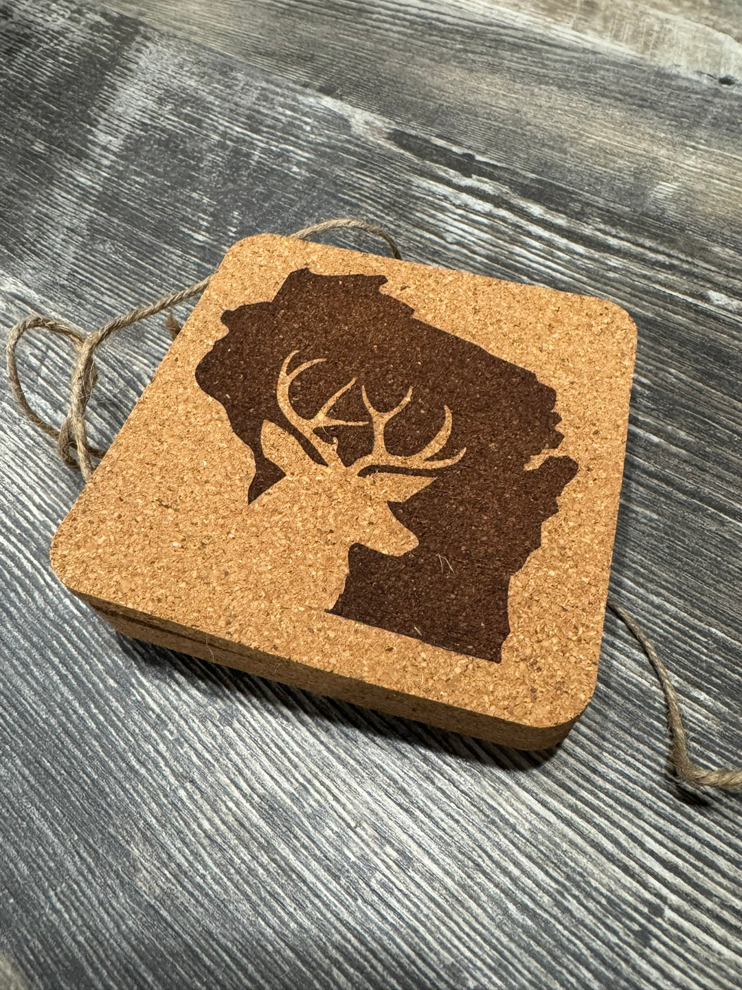 Cork coaster with silhouette of Wisconsin with negative silhouette of antlered dear on the Wisconsin silhouette. Quite a nice image.