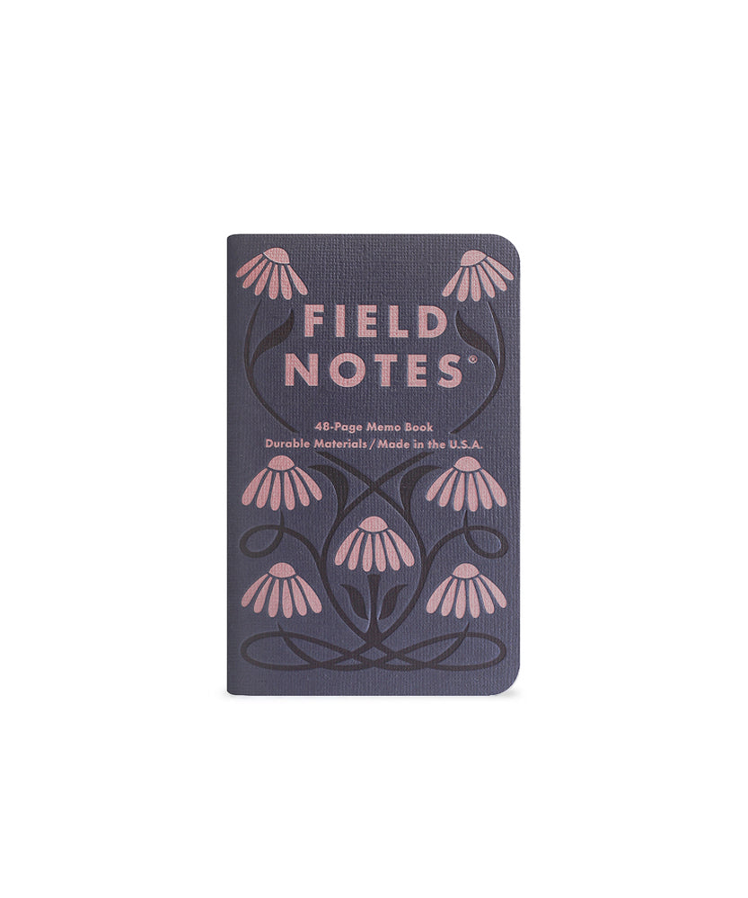 Memo book with seven abstract flowers  in pink that are connected with  a black vine, and the text 'Field Notes' on a dark blue background.