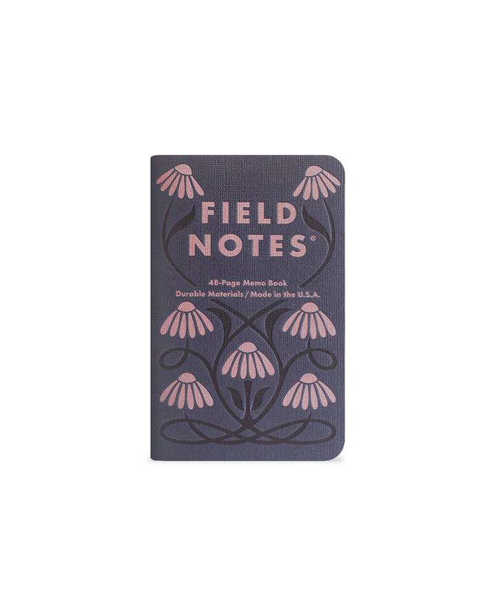 Memo book with seven abstract flowers  in pink that are connected with  a black vine, and the text 'Field Notes' on a dark blue background.