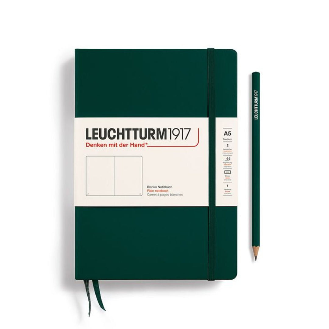 A Leuchtturm1917 A5 hardcover plain page notebook in forest green with a white label on the front, shown closed with an elastic closure and ribbon bookmark. A matching forest green pencil is placed vertically to the right.