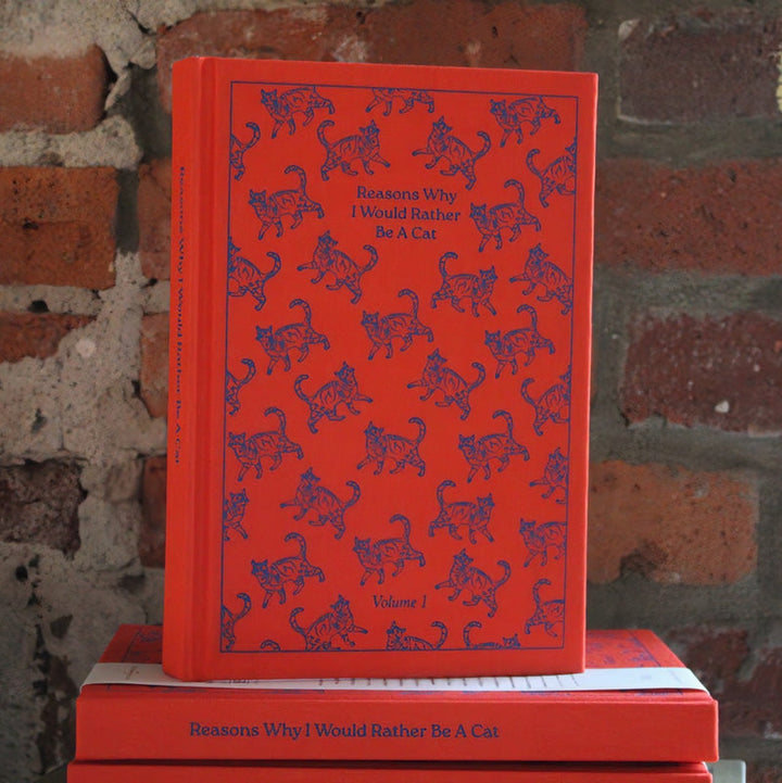 The image of purple cats, some facing left, some right, repeated over the red cover. The title is repeated on the spine and "Volume 1" appears at the bottom center. 