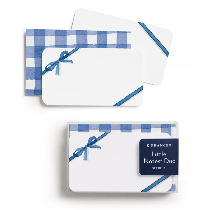 Little note with a blue ribbon at top left, with a bow, and bottom right, on top of a blue and white checked envelope.