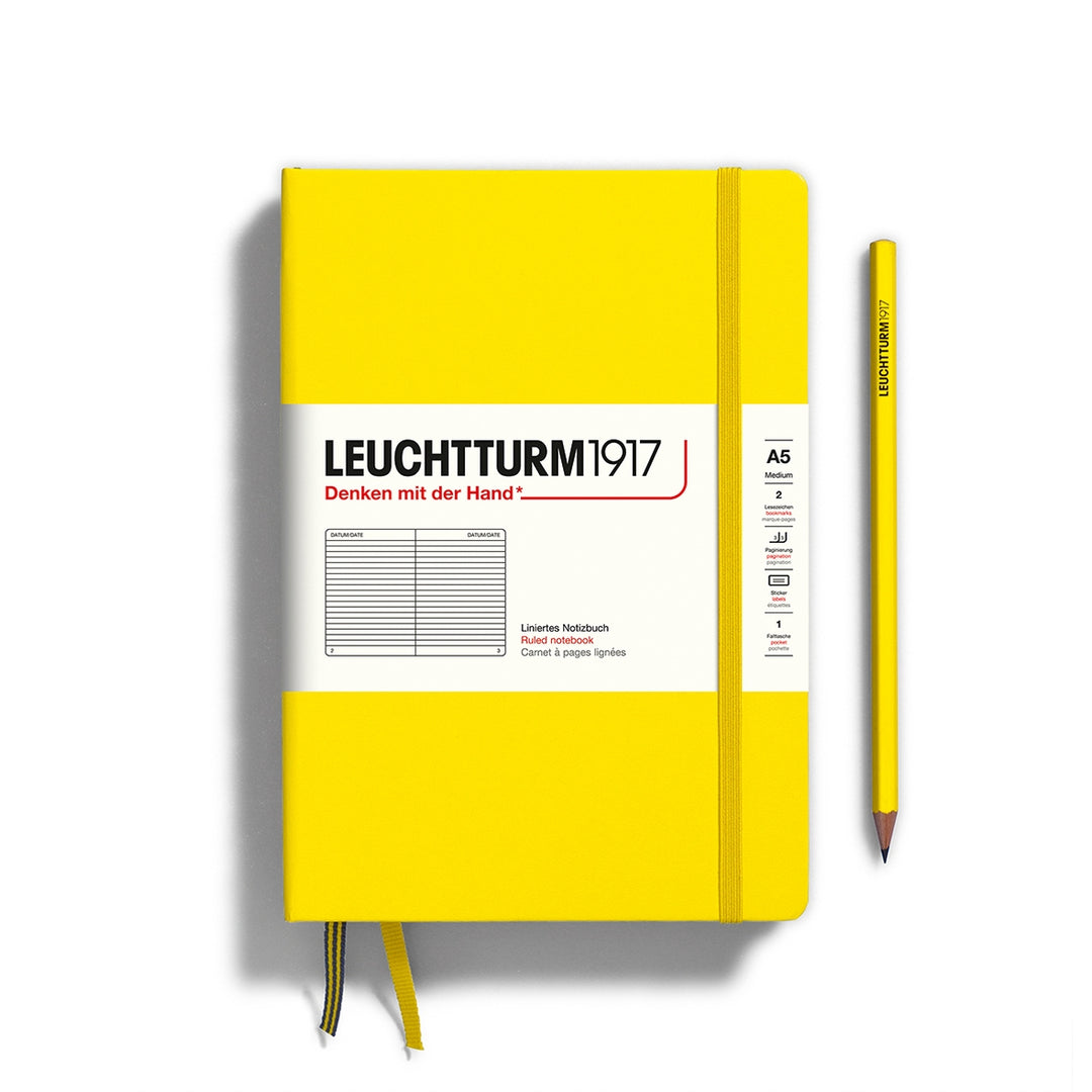 A lemon yellow Leuchtturm1917 A5 ruled page pocket notebook with a white front label and yellow elastic closure,  next to a lemon yellow Leuchtturm1917 pencil.