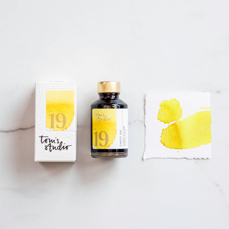 The box of Tom's Studio 19 Lemon Yellow Ink next to its bottle and a paint swatch.