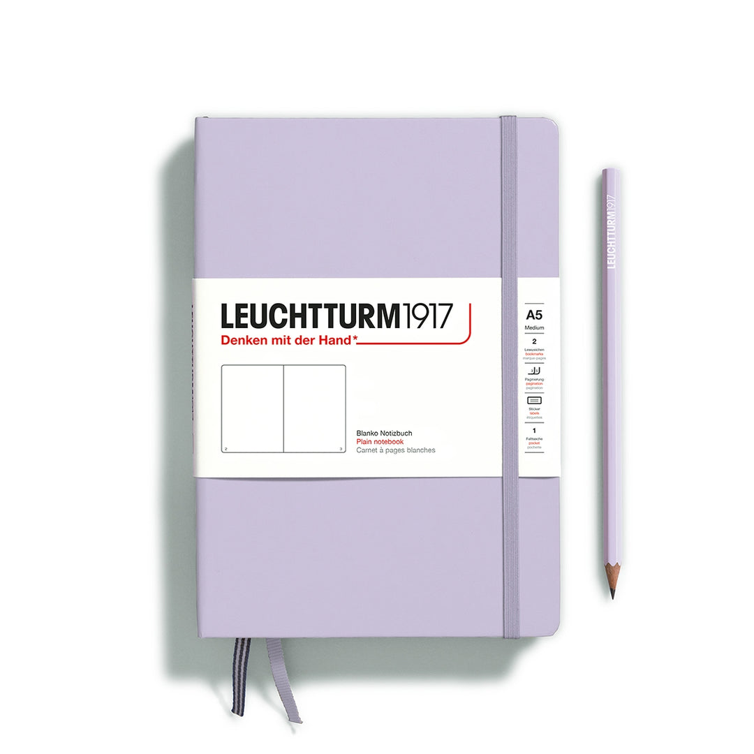 A lilac Leuchtturm1917 A5 plain page pocket notebook with a white front label and lilac elastic closure,  next to a lilac Leuchtturm1917 pencil.