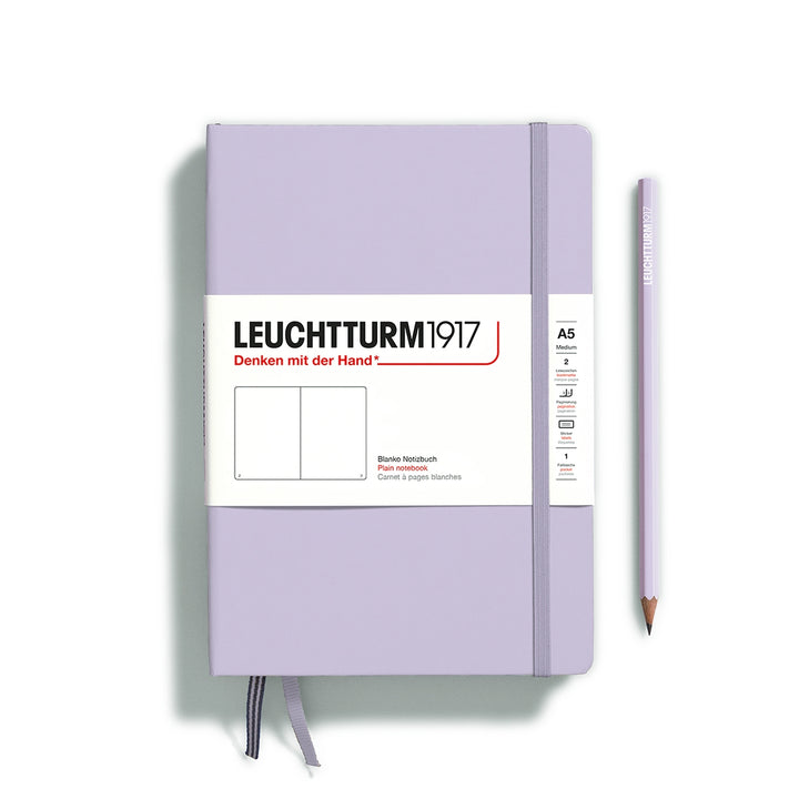 A lilac Leuchtturm1917 A5 plain page pocket notebook with a white front label and lilac elastic closure,  next to a lilac Leuchtturm1917 pencil.