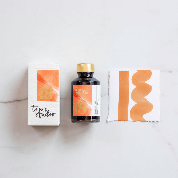 The box of Tom's Studio 08 Marmalade Ink next to its bottle and a paint swatch.